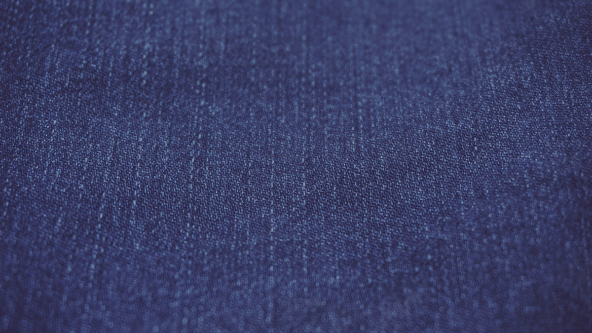 A close-up texture shot of dark blue denim fabric.