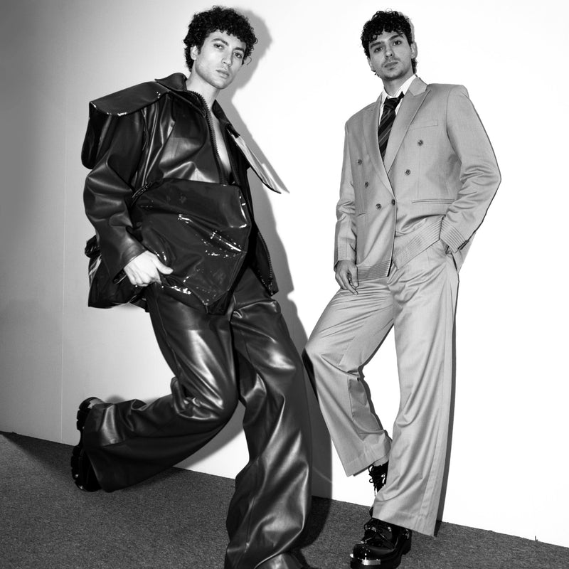 Two men in stylish suits posing against a plain background